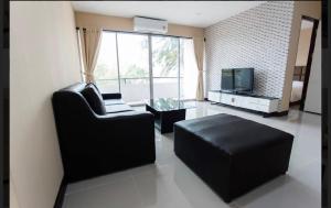 a living room with a black couch and a tv at MountainviewKhaoyai in Ban Khanong Phra Klang (1)