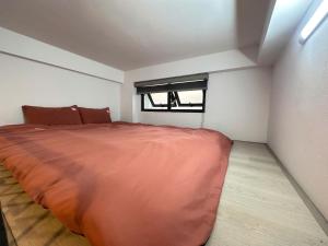 a bedroom with a large orange bed with a window at Urban Nest - Đông Ngạc in Hanoi