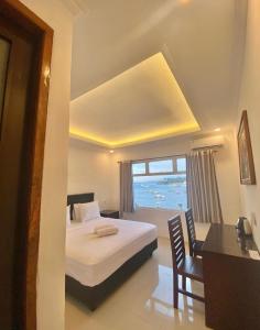 a bedroom with a bed and a desk and a window at Anugrah Hotel Teluk Nara in Teluknarat