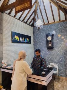 a man and a woman standing at a counter at Wisma Lovebird in Kalianget