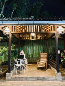 a man sitting at a table with a laptop on a patio at Wisma Lovebird in Kalianget