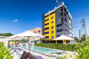 a swimming pool with umbrellas and a yellow building at Phuket Five Fortune Holiday Hotel in Rawai Beach +96 photos