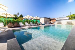 a swimming pool with chairs and umbrellas on a building at Phuket Five Fortune Holiday Hotel in Rawai Beach
