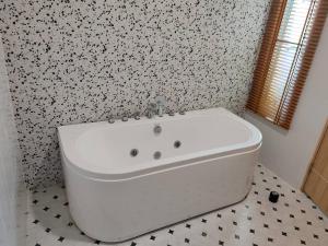 a white bath tub in a bathroom with floral wallpaper at The Triple Little House in Ban Nong Chang Nua