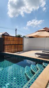 a swimming pool with two chairs and an umbrella at Pana Villa Koh Lanta in Ban Ai Dao