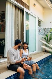 a man and woman sitting next to a swimming pool at Okka by Raho - A colonial style villa in Coorg in Siddapur