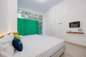 a bedroom with a large bed with a green curtain at Urbanview Hotel near Exit Tol BSD in Ciater-hilir