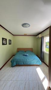 a bedroom with a bed with a blue comforter and a window at Liina House in Ko Yao Noi
