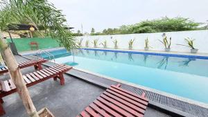 a swimming pool with two wooden benches next to it at Sunset Villa in Hambantota +21 photos