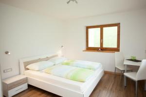a white bedroom with a bed and a desk and a window at Appartement Bachguter in Avelengo