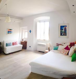 a white bedroom with a large bed and a couch at Lovely Central Apartment in Talamone
