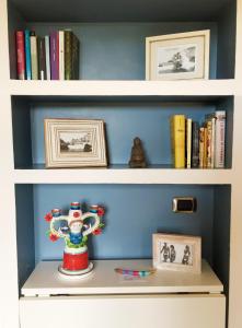 a book shelf with books and a vase on it at Lovely Central Apartment in Talamone +5 photos