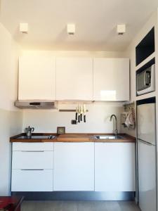 a kitchen with white cabinets and a sink at Lovely Central Apartment in Talamone