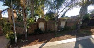a brick house with palm trees in front of it at Roxana Guestrooms in Johannesburg