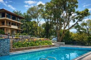 a swimming pool in front of a house at Nirjhara Coorg in Somvārpet