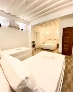 a white bedroom with two beds and a bathroom at Ahava Boutique Hotel in Pooc