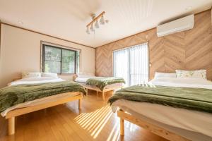 two beds in a room with wooden walls at 天然温泉-富士山パノラマビュー-プライベートデッキで非日常体験を-伊豆の温泉付き貸別荘-中伊豆noie in Izu