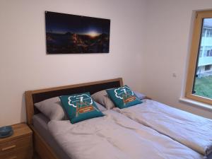 a bed with two pillows on it next to a window at Haus am Sonnenhang by Schladmingurlaub in Schladming