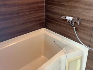 a bathtub with a hose hooked up to a shower at フレグランスショーワ in Matsue