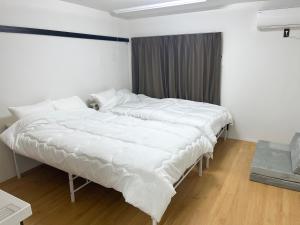 two beds in a room with white sheets at フレグランスショーワ in Matsue