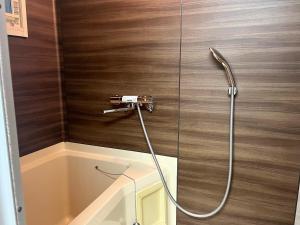 a shower with a hose attached to a wall at フレグランスショーワ in Matsue