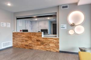 an office lobby with a stone counter and mirrors at ECHO Suites Extended Stay by Wyndham Dallas Plano Richardson in Plano