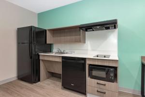 a kitchen with a black refrigerator and a sink at ECHO Suites Extended Stay by Wyndham Dallas Plano Richardson in Plano