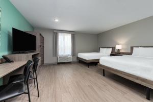 a hotel room with two beds and a flat screen tv at ECHO Suites Extended Stay by Wyndham Dallas Plano Richardson in Plano +19 photos