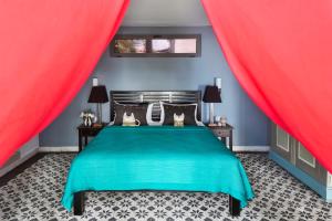 1 dormitorio con cama verde y cortinas rojas en Owl and the Pussycat Hotel & Restaurant, en Unawatuna