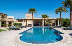 a swimming pool with palm trees and a building at Catalina in Alcudia
