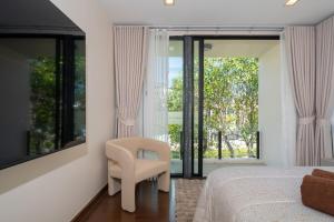 a bedroom with a bed and a chair and a window at Luxury 5 bed Laguna Park no Pool in Bang Tao Beach