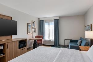 a hotel room with a bed and a flat screen tv at Hampton Inn Owensboro in Owensboro