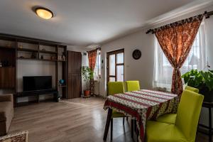 a living room with a table and green chairs at Grandma’s Cottage in Săcele