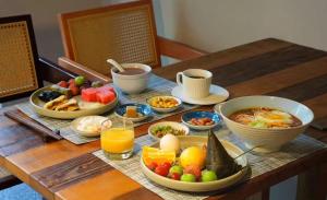 a table topped with bowls of breakfast foods and juice at YunXi ChanYi Forest Soup Spring Resort Hotel ,Provides pick-up service and tea leaves,Drink Chinese wild tea leaves in Emeishan City