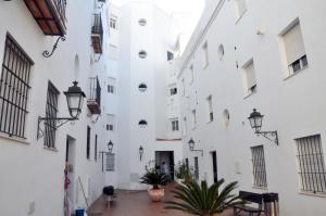 een wit gebouw met ramen en een binnenplaats met planten bij Atiko Welcome in Arcos de la Frontera