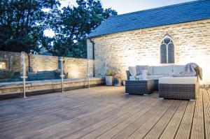 a deck with a couch and chairs in front of a church at Scotney Place in Stamford