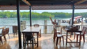 a patio with tables and chairs and a view of the water at Libong River View in Ban Maphrao (2)