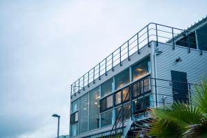 a blue building with a balcony and palm trees at Yokosuka Sky Grey -横須賀のビーチフロントベース- in Yokosuka
