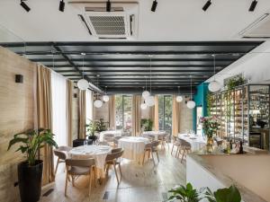 a restaurant with white tables and chairs and large windows at City Park Hotel in Skopje