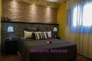 um quarto com uma cama grande e uma parede de tijolos em Apartamentos Adarve Toledo em Toledo
