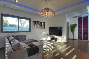 a living room with a couch and a tv and a chandelier at S Villa Place נהריה in Nahariyya