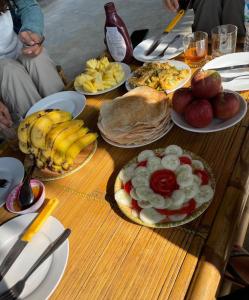 a wooden table topped with plates of food and fruit at MaMa ShuShu Homestay in Sapa +25 photos