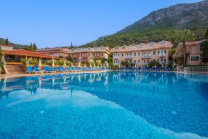 a large swimming pool with houses and mountains in the background at Ölüdeniz Turquoise Hotel - All Inclusive in Oludeniz +52 photos