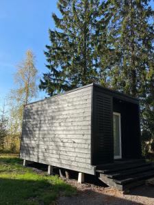 a tiny house sitting in the grass near some trees at RUSKA-mökki in Tyrnävä