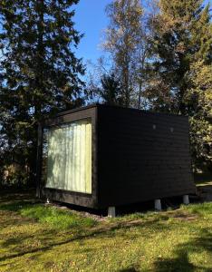 a black house in a field with trees at RUSKA-mökki in Tyrnävä