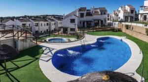 a swimming pool in the middle of a yard with houses at El Rinconcito in El Ronquillo