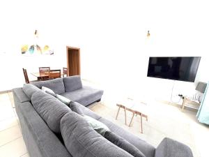 a living room with a gray couch and a flat screen tv at Nashu Three bedroom Townhouse in Dambani