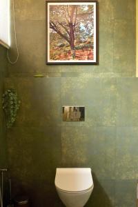a bathroom with a toilet and a painting on the wall at A Modern 2BHK Private Villa in Vagator - Valenades in Vagator