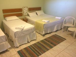 a hotel room with two beds and a chair at Pousada Camping Quedasdagua in Barra do Rio Abaixo +44 photos