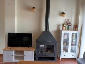 a living room with a wood stove and a tv at El Rinconcito in El Ronquillo